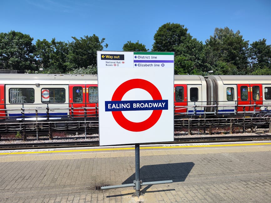 A rectangular sign displaying the London Underground roundel symbol, consisting of a red circle with a blue horizontal bar across the center. The blue bar features white text reading 'HYDE PARK CORNER'. The sign is mounted on a dark green background panel, which is part of a paneling structure framed by metal supports on either side. The surrounding environment appears to be an indoor or sheltered area, with a paneled surface above and some visible metal edges, indicating it might be part of a public transit or station signage setup. The lighting is even, with no harsh shadows or glare, highlighting the clear visibility of the sign's colors and text. The sign and its installation are neutral and professional in appearance, with no additional objects or decorations in view, emphasizing its function as directional or location indication within a transportation context relating to the London Underground network, indirectly supporting awareness of local transit points and associated signage.
